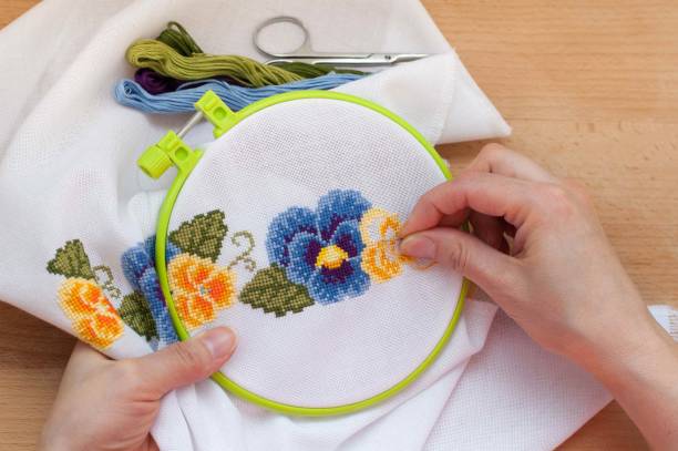 le mani femminili ricamano fiori sulla tela. tecnica del punto croce. - needlecraft product embroidery cross stitch flower foto e immagini stock