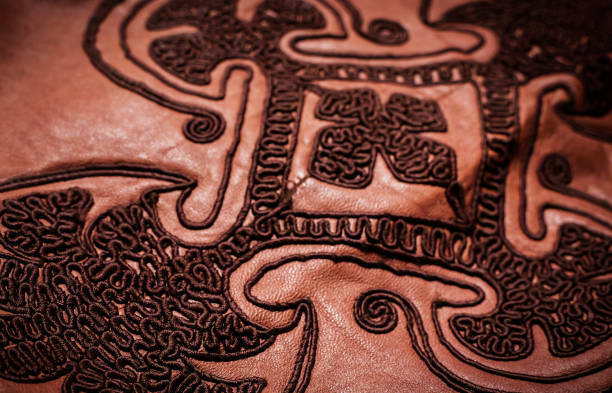 istock embroidered ornament on a brown leather texture 933871940