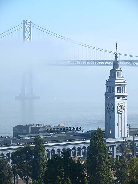 ferry building & bay bridge di nebbia sopra - bay bridge san francisco county san francisco bay area landscaped foto e immagini stock