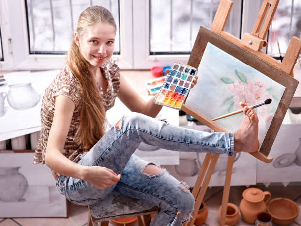 Artist painting on easel in studio. Girl paints with brush. stock photo
