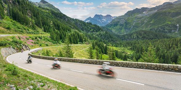 A group of motorcyclists travels on the Susten Pass mountain road through the Alps in summer.