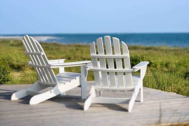 Adirondack chairs overlooking grassy beach and ocean stock photo