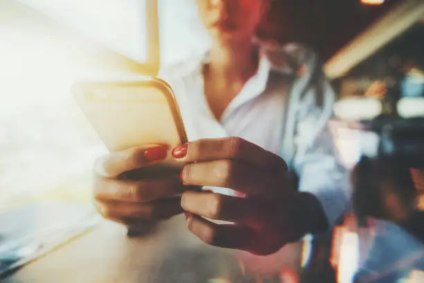 Photo of Female hands holding cellphone in a restaurant