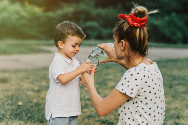 mère de verser son enfant limonade - water child bottle little boys photos et images de collection