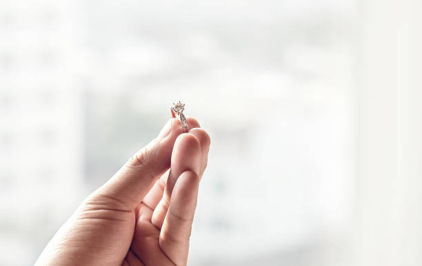 istock hand hold diamond ring with blur city background. 933932524