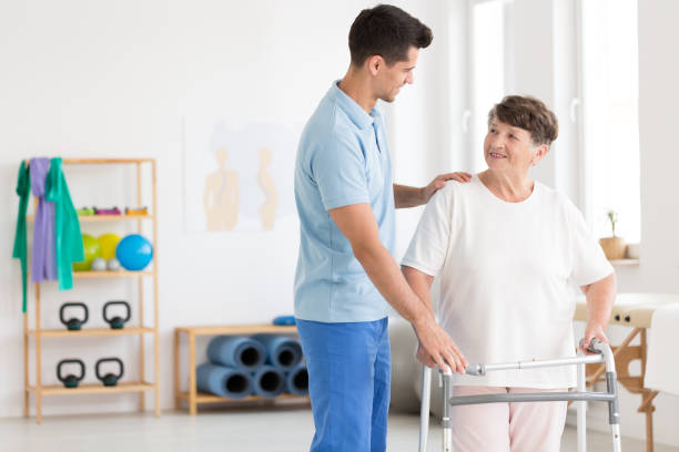 Elderly woman and caring physiotherapist Caring physiotherapist supporting elderly woman with walking frame hip replacement stock pictures, royalty-free photos & images