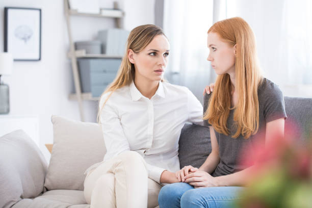 Girl confessing problems to sister Teenage girl on a sofa, confessing problems to her older sister and getting support and advice self harm photos stock pictures, royalty-free photos & images