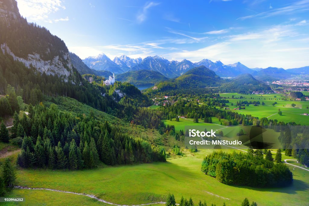 Famous Neuschwanstein Castle visible in the distance, located on a rugged hill above the village of Hohenschwangau in southwest Bavaria, Germany Famous Neuschwanstein Castle visible in the distance, located on a rugged hill above the village of Hohenschwangau near Füssen in southwest Bavaria, Germany Munich Stock Photo