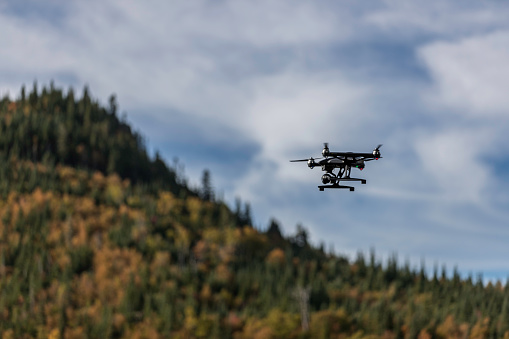 DSLR picture of a Drone flying over a Boreal Forest in Quebec on beautiful fall day. The drone is a Yuneec Typhoon Q500+ equipped with a 4k camera.