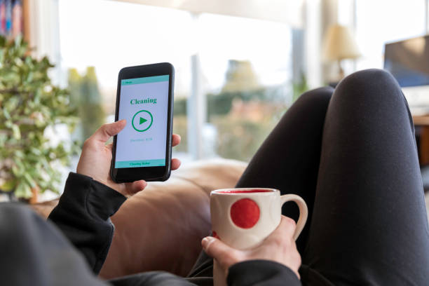 istock Woman Using Home Robot Cleaning App on Mobile Phone 933969992