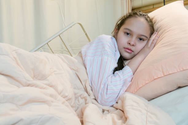 istock Mixed race tween girl in hospital bed, looking at camera 933972344