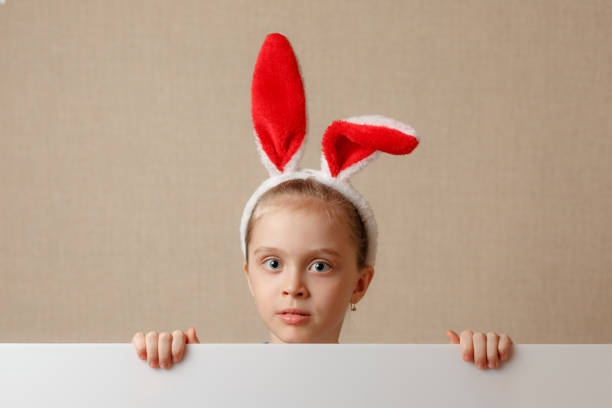 istock A nice little girl is looking because of an empty banner in which you can insert any text. 934018012