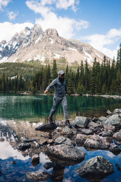 istock Man is walking on rocks in front of lake and mountains 934025068