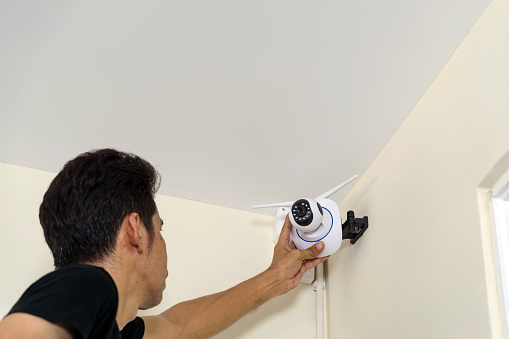 Technicians are installing a wireless cctv camera on the roof, can connect to the Internet, and control the camera via a smartphone or tablet.
