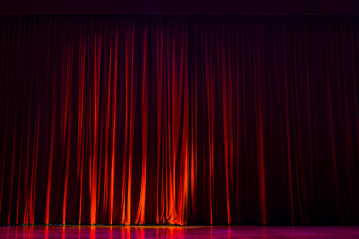 Red velvet curtains with the lights of the show and the wood flooring parquet.