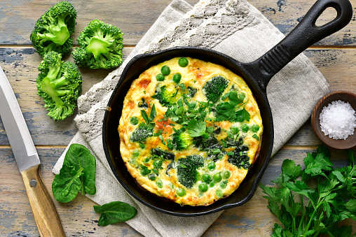 Spring omelette with green vegetables (broccoli, sweet pea and spinach) in a skillet