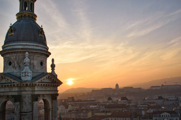 tramonto dalla basilica di santo stefano con una delle sue torri e il castello di buda sullo sfondo - budapest royal palace of buda architectural styles architecture foto e immagini stock