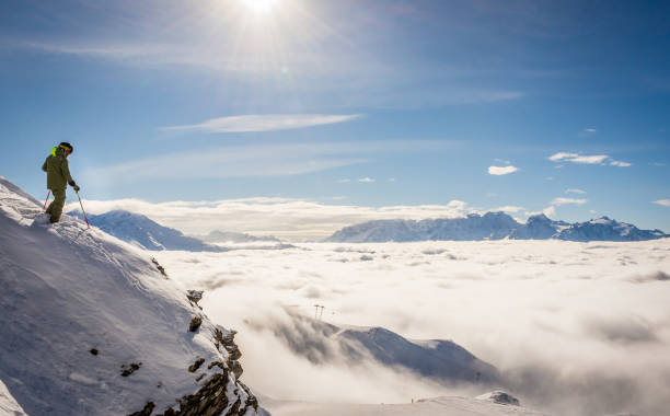 sciatore in piedi su una roccia sopra le nuvole - skiing activity snow alpine skiing foto e immagini stock