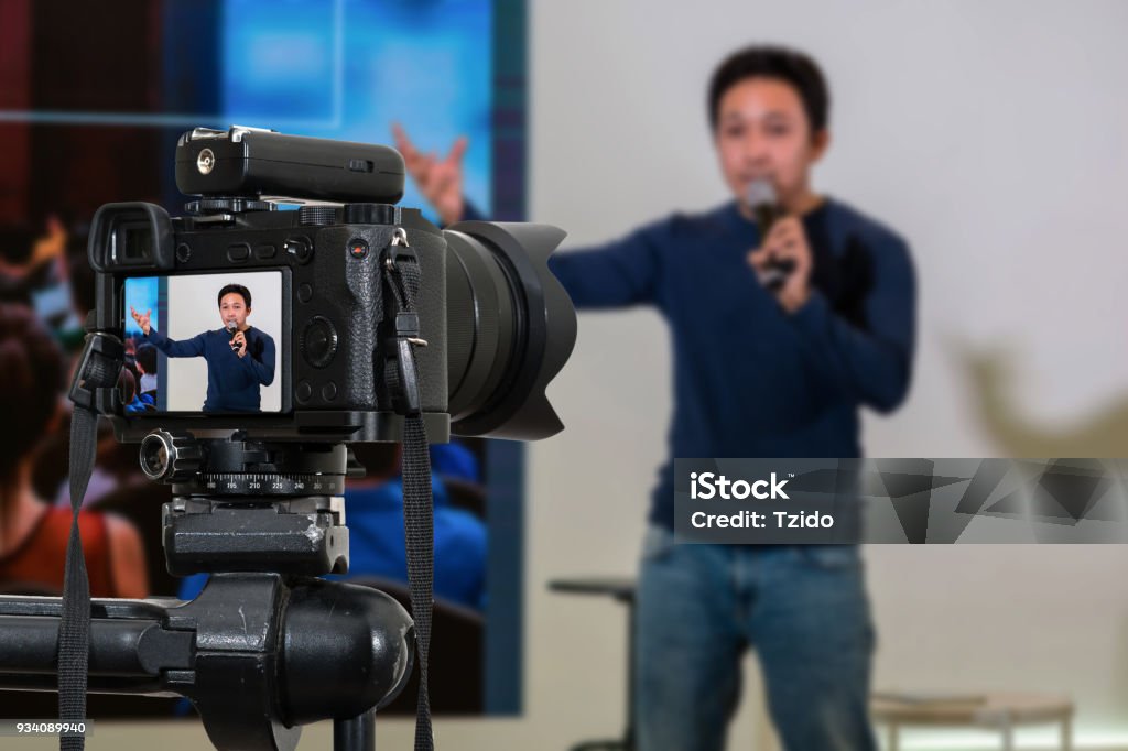 Professional digital Mirrorless camera with microphone on the tripod recording video blog of asian Speaker on the stage seminar, Camera for photographer or Video and Technology Live Streaming concept Home Video Camera Stock Photo