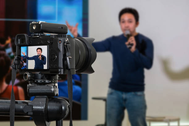 Professional digital Mirrorless camera with microphone on the tripod recording video blog of asian Speaker on the stage seminar, Camera for photographer or Video and Technology Live Streaming concept stock photo