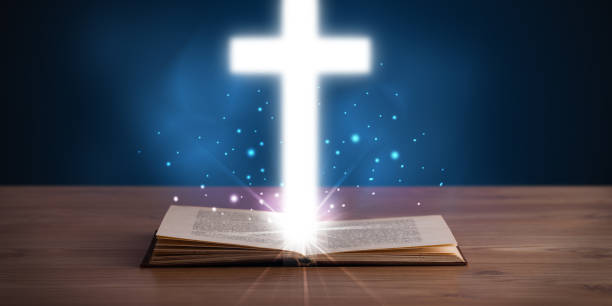 istock Open holy bible with glowing cross in the middle 934095576