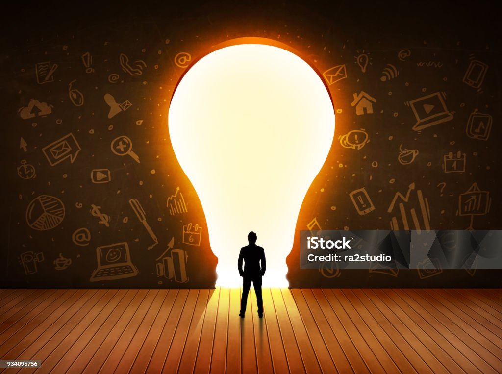 Business man looking at bright light bulb in the wall Business man looking at bright light bulb in the wall concept Education Stock Photo