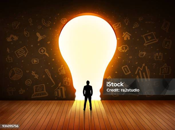 Business Man Looking At Bright Light Bulb In The Wall Stock Photo - Download Image Now