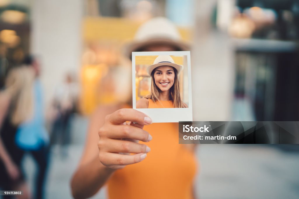 Woman showing instant photo to the camera Young woman showing instant self portrait to the camera Instant Print Transfer Stock Photo