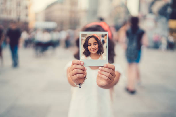 Little girl showing polaroid self portarit Kid on vacation holding instant photo to the camera cute id pictures stock pictures, royalty-free photos & images