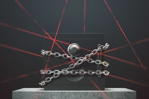 Closed safe box standing against a black wall on a marble table. Chains. Laser rays. Concept of security and economics. 3d rendering mock up