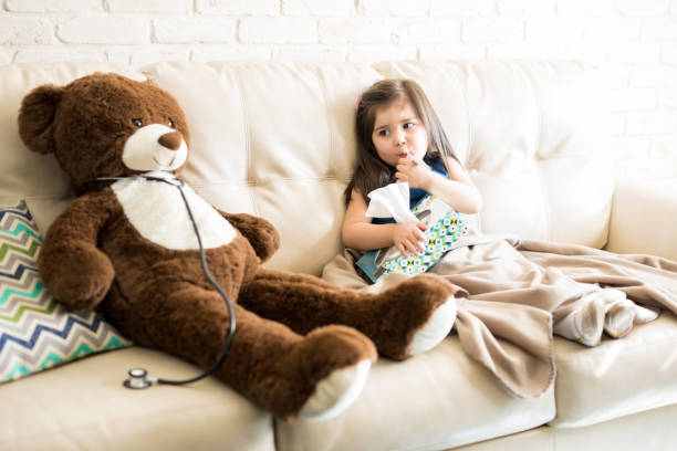 sick girl with doctor teddy bear on sofa - people purity personal accessory handkerchief imagens e fotografias de stock