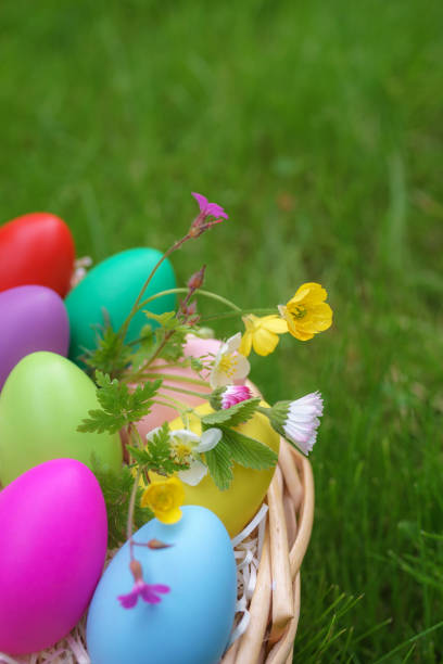 istock Colorful eggs with springtime flowers in basket on green grass 934150536
