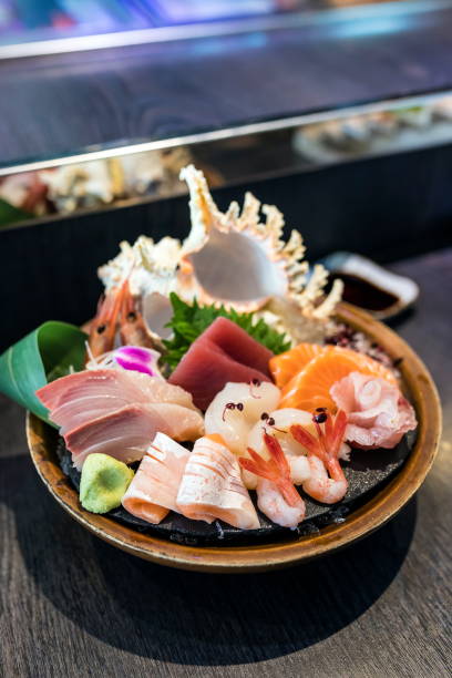 istock Selective focus decorated sashimi set in a bowl with ice and conch shell near the chef bar. 934153540