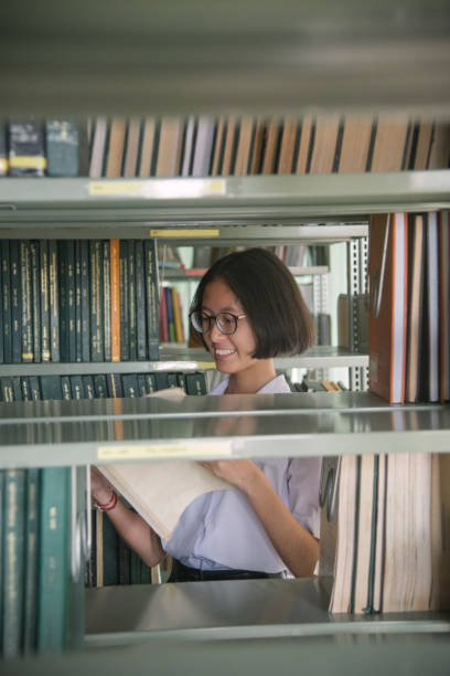 istock Asian student girl reading book in public library 934158396