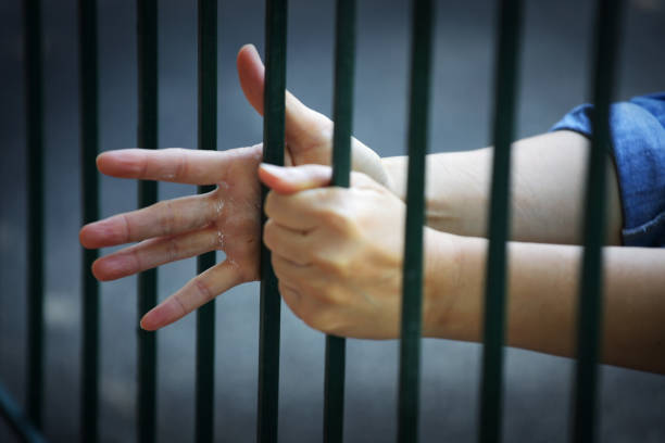 istock hands of prisoner in jail background. 934179558