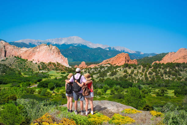 Happy family enjoying beautiful mountain view on vacation hiking trip. Happy family with arms around each other enjoying beautiful mountain view on  hiking trip. Beautiful red mountains and green hills in Colorado. Garden of the Gods, Colorado Springs, Colorado,  USA. colorado springs photos stock pictures, royalty-free photos & images