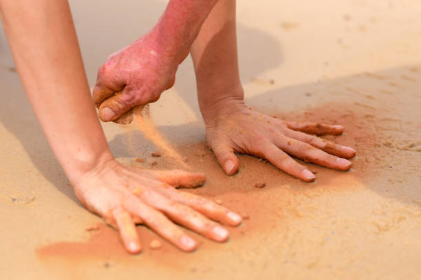 manos de mujer creando formas con arena roja en la playa de estilo arte aborigen - aboriginal art aborigine rock fotografías e imágenes de stock