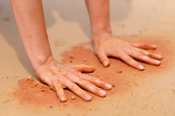 manos de mujer creando formas con arena roja en la playa de estilo arte aborigen - aboriginal art aborigine rock fotografías e imágenes de stock