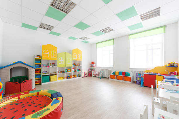 istock Spacious white game room in the kindergarten with toys, two large windows and tables for classes 934227374