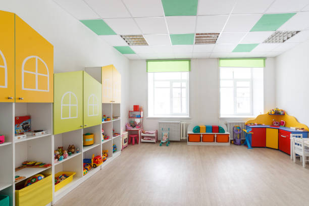 istock Spacious white game room in the kindergarten with toys, two large windows and tables for classes 934227398