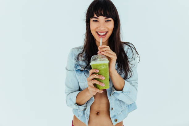 美しい女性飲酒の新鮮な緑のスムージー - smoothie drinking women drink ストックフォトと画像
