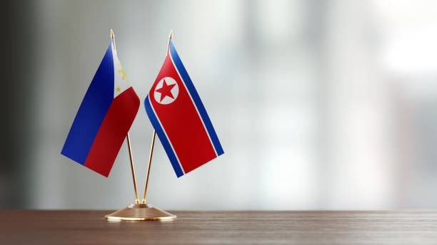 istock Philippines And North Korean Flag Pair On A Desk Over Defocused Background 934245082
