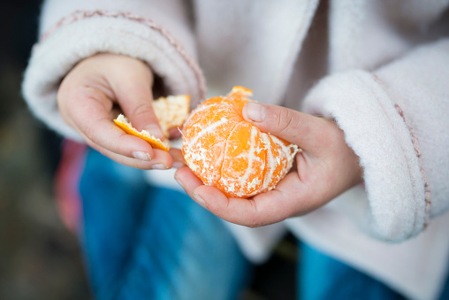 Little girl peeling orange peel