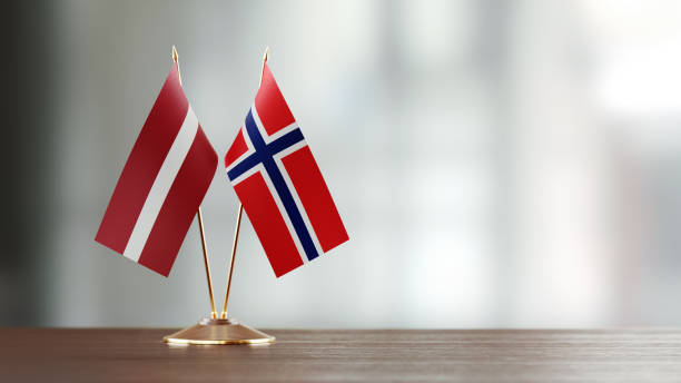 istock Latvian And Norwegian Flag Pair On A Desk Over Defocused Background 934256464