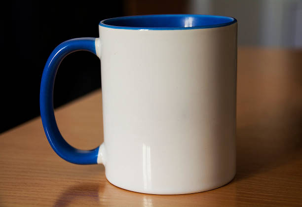 White cup with blue handle on wooden table on blurred background