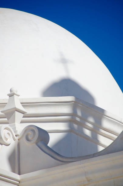 Architectural Detail of San Xavier del Bac Mission The San Xavier del Bac Mission stands on the Tohono O'odham Indian Reservaton near Tucson, Arizona.  The building itself is full of interesting architectural details.  Pictured here is a shadow cast by a tower with a cross onto the dome of the chapel. tohono o'odham stock pictures, royalty-free photos & images