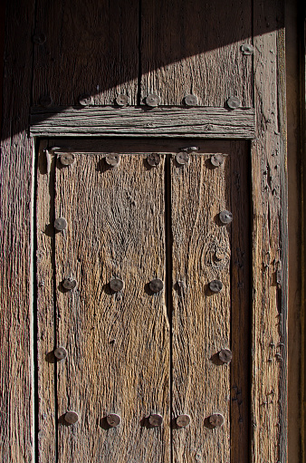 The San Xavier del Bac Mission stands on the Tohono O'odham Indian Reservaton near Tucson, Arizona.  The front door shows its age with raised wood grain and metal discs from another time.