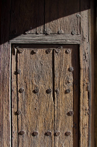 Front Door of San Xavier del Bac Mission The San Xavier del Bac Mission stands on the Tohono O'odham Indian Reservaton near Tucson, Arizona.  The front door shows its age with raised wood grain and metal discs from another time. tohono o'odham stock pictures, royalty-free photos & images