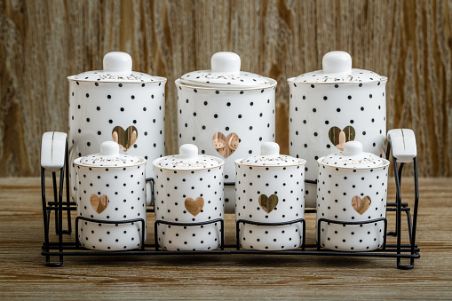 Black dotted white porcelain spice jars with heart pattern on brown background