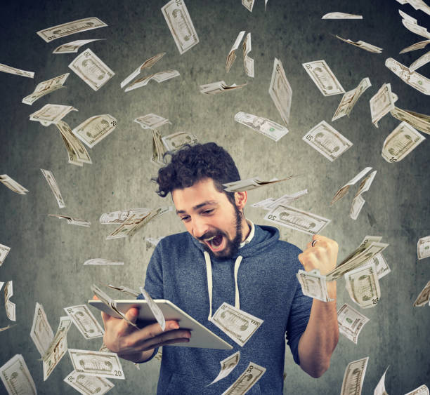 istock Successful man with tablet under money rain 934271070
